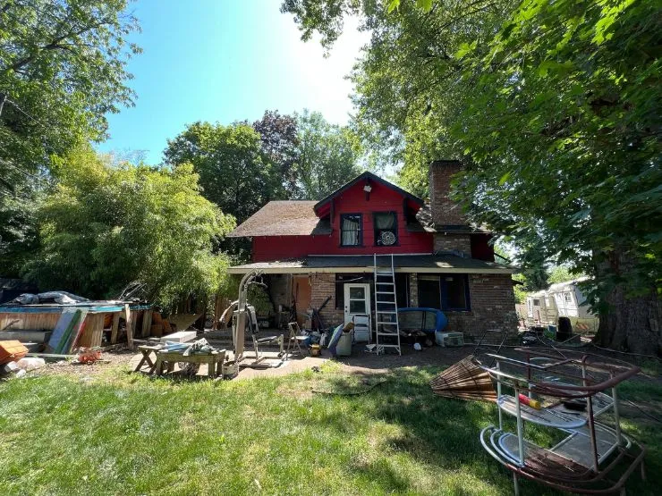 A Vancouver, WA house with peeling paint, a sagging porch roof and a yard full of stored belongings