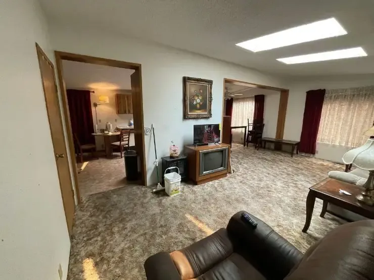 The living room of an inherited Auburn, WA home, still furnished, with dated carpet